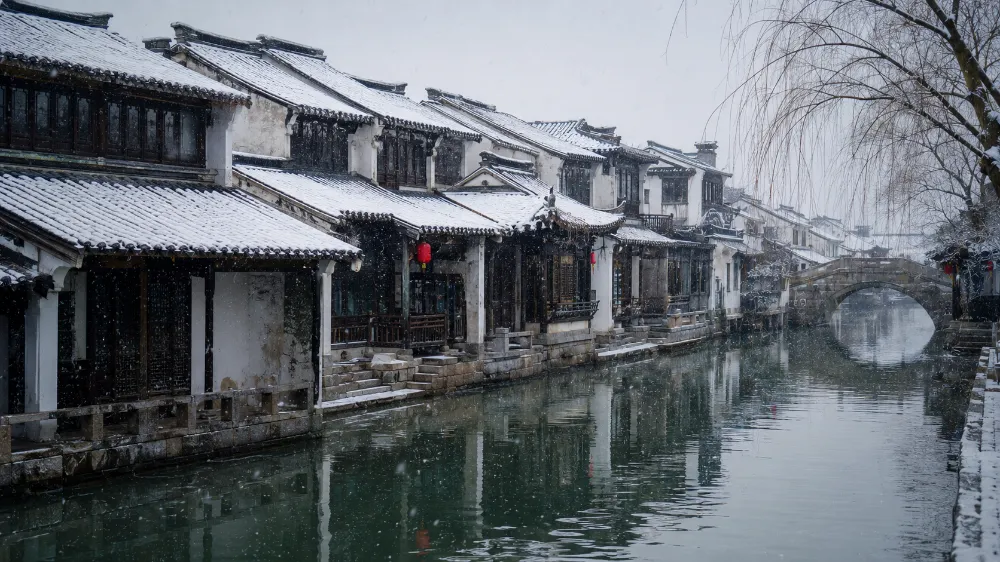 Light snow on traditional rooftops along Pingjiang Road canal in Suzhou old city in December