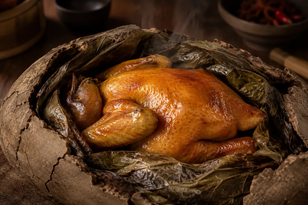 Beggar's Chicken wrapped in lotus leaf being cracked open at the table