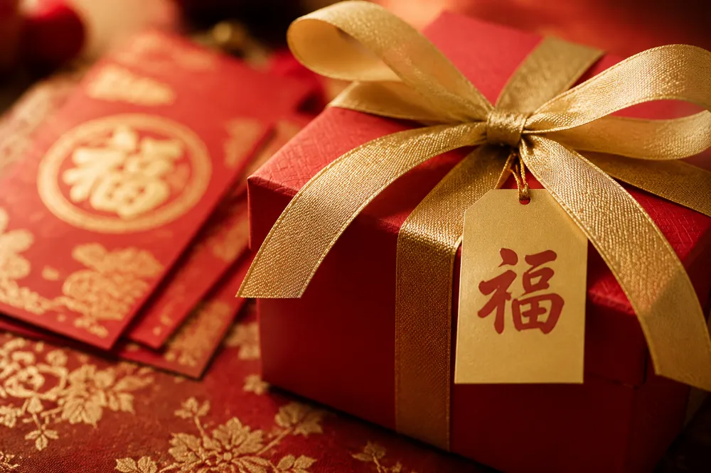 A red and gold wrapped Chinese New Year gift box with a Fu character tag and red envelopes