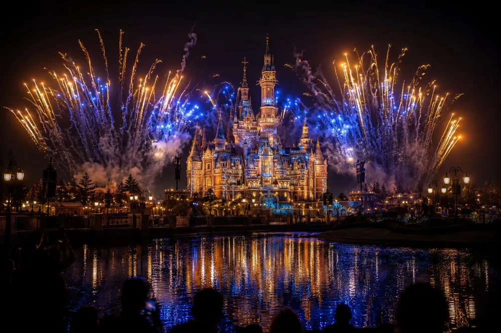 Enchanted Storybook Castle at Shanghai Disneyland lit up by the ILLUMINATE nighttime fireworks show over the lake
